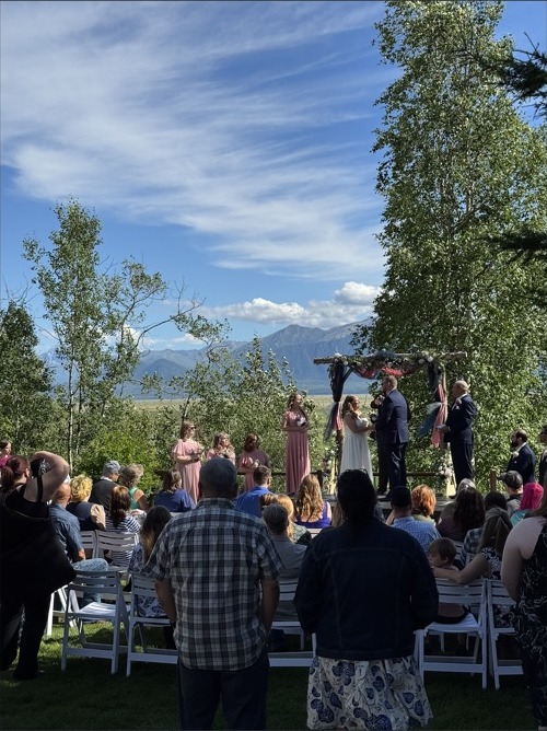 Outdoor wedding ceremony framed by an arch and Alaska mountains